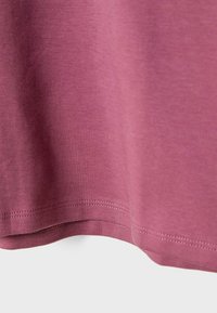 Hem of a soft, muted purple fabric with visible double-stitched seams against a light background.