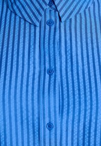 Modrá košile s vertikálními tmavě modrými pruhy, zapínání na knoflíky vpředu a špičatým límcem.
