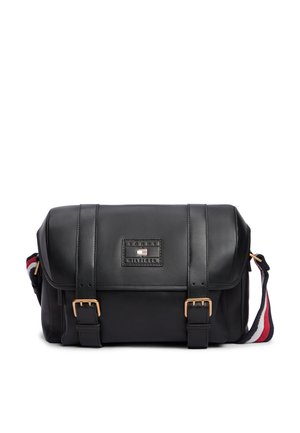 Sac messager en cuir noir avec des sangles à boucle à l'avant et une bandoulière rayée rouge, blanche et bleue réglable.