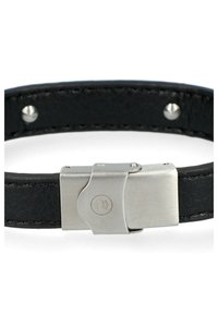 Czarna skórzana bransoletka z zapięciem ze stali nierdzewnej, na którym znajduje się logo. Pasek jest gładki, z widocznym przeszyciem i nitami.