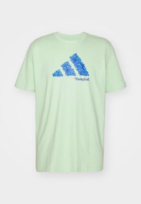T-shirt in cotone verde chiaro con un design grafico blu che rappresenta tre strisce e la parola "Basketball" stampata sotto. Maniche corte, collo tondo.