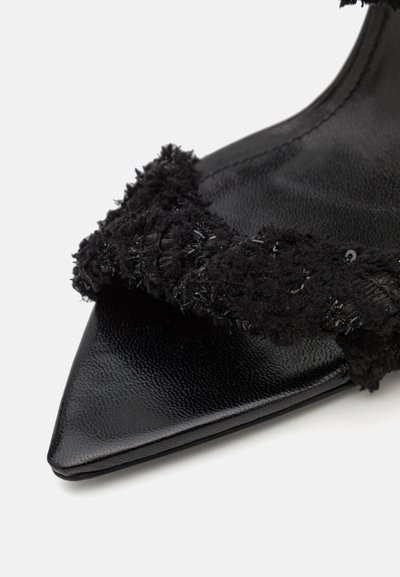 Sorte spidse sko med en tekstureret stofrem med en fluffy finish, sat på en slank sort lædersål. Accenterne er minimalistiske.