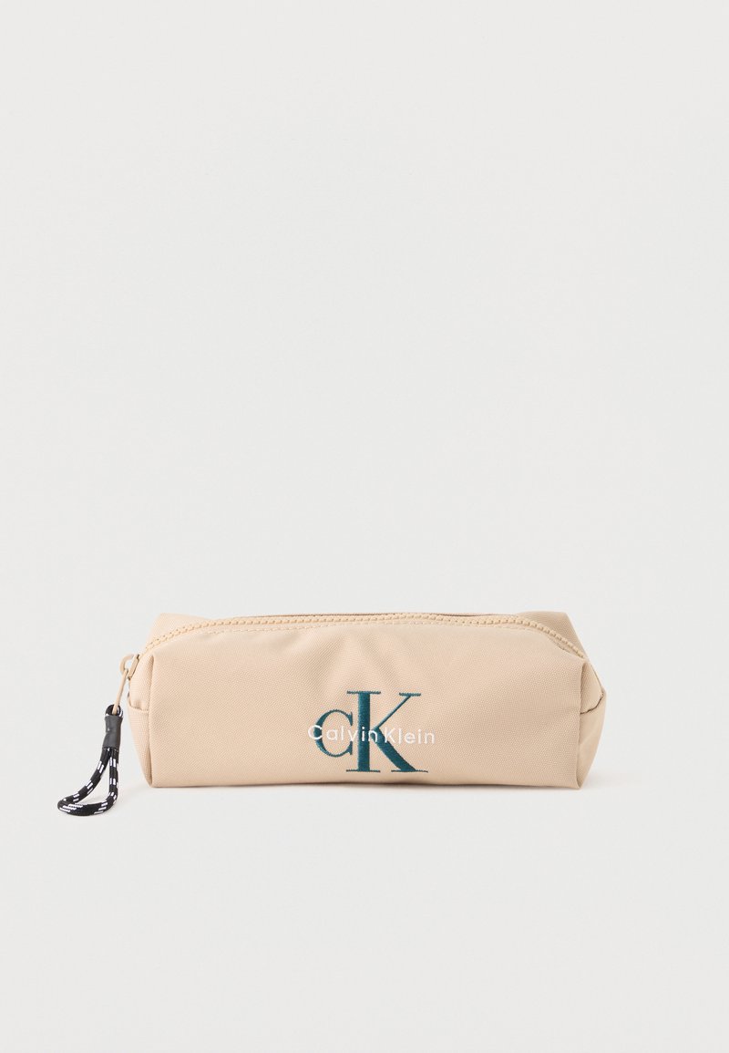 Ορθογώνια μπεζ θήκη με φερμουάρ, με μαύρο και άσπρο λουράκι στο φερμουάρ και σκούρο πράσινο λογότυπο "CK Calvin Klein" στο μπροστινό μέρος.