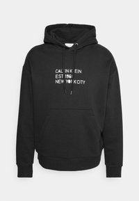 Felpa nera in misto cotone, con tasca a marsupio frontale, cappuccio con cordino e testo bianco: "CALVIN KLEIN EST 1961 NEW YORK CITY."