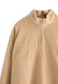 Beige fleece-poolo, jossa on puolivetoketjukiinnitys, korkea kaulus ja sileä pinta. Sisältää vaakasauman rinnassa.