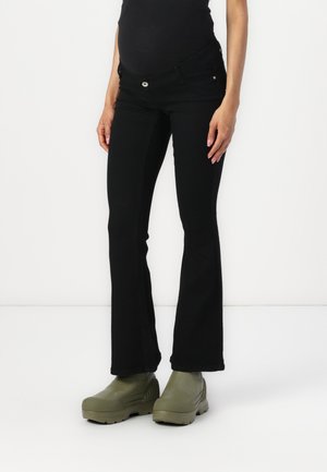 Black flared maternity jeans with a stretchy waistband, featuring two front pockets and a button closure, paired with green platform boots.