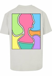 Hvid kortærmet t-shirt med et farverigt abstrakt design på ryggen, med former i pink, blå, grøn, orange og lilla, der er omkranset af sort.