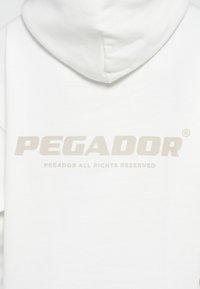 Weißer Hoodie mit einem großen, hellgrauen Textlogo "PEGADOR" und dem Aufdruck "PEGADOR ALL RIGHTS RESERVED" auf der Rückseite.