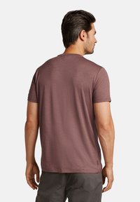 Camiseta de manga corta en color burdeos, hecha de tejido texturizado, con cuello redondo y dobladillo recto, vista desde la parte de atrás.