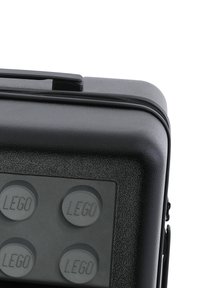 Svart hård fodral med en texturerad yta, med en dragkedja och fyra upphöjda LEGO-byggstenar på frampanelen.