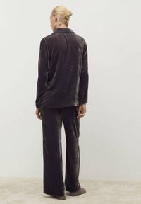 Conjunto de pijama de terciopelo en gris oscuro, que incluye una camisa de botones de manga larga y pantalones de pierna ancha, con una textura suave y un diseño minimalista.