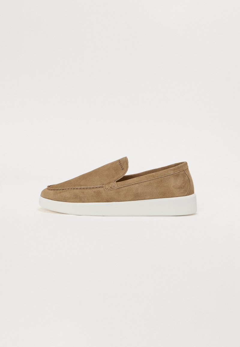 Suede slip-on shoes in light brown with a rounded toe and a white rubber sole. Features stitching accents and a padded collar for comfort.