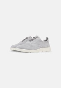 Scarpe in suede grigio con punta arrotondata, cinque occhielli e suola in gomma bianca. Presentano un taglio basso e un'etichetta sul tallone.