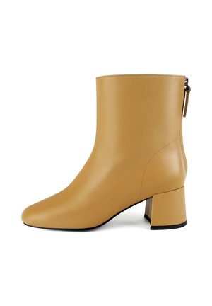 Svetlo rjava usnjena gležnjarja s kvadratnim nosom in blok peto. Ima gladko teksturo in zadrgo na zadnjem delu.