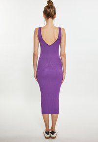 Rochie midi rib trim violet cu un design V la spate, fără mâneci, și siluetă ajustată, asortată cu pantofi sport albaștri și negri.