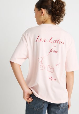 Ružové bavlnené tričko s červeným nápisom "Love Letters from Paris" a ilustráciami martini pohára, obálky a kvetu. Krátke rukávy.