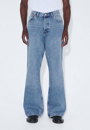 Light blue oversized denim jeans with a high waist, wide legs, and contrasting stitching. The fabric has a slight faded texture.