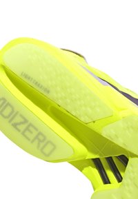 Felgekleurde gele hardloopschoenen met een gestructureerde zool, gestroomlijnd ontwerp en "LIGHTTRAXION" branding op de buitenzool.