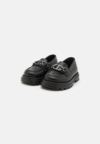 Mocasines de cuero negro con suela de goma gruesa, con un acento decorativo de cadena en el empeine. Textura suave, diseño de punta redonda.