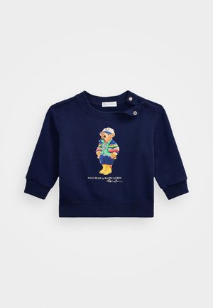 Marineblå sweatshirt til tumling med illustration af bjørn iført stribet jakke og gule støvler, knapper ved skulderen, lange ærmer.