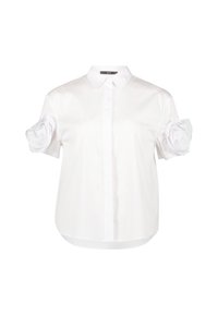 Camicia bianca a maniche corte realizzata in tessuto morbido, con colletto e un unico dettaglio floreale in tessuto sulla manica sinistra.