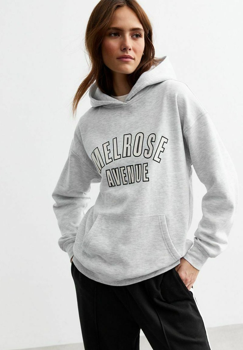 Gray sweatshirt with a hood, featuring "MELROSE AVENUE" in bold black text. Ribbed cuffs and a front pocket. Smooth texture.