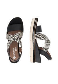 Black and white cross-strapped sandals with a textured fabric upper, a cushioned footbed, and a chunky cream sole.