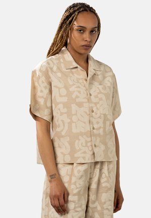 Short-sleeve, button-up shirt in light beige with white abstract patterns. Smooth fabric, relaxed fit, and patch pocket on the front.