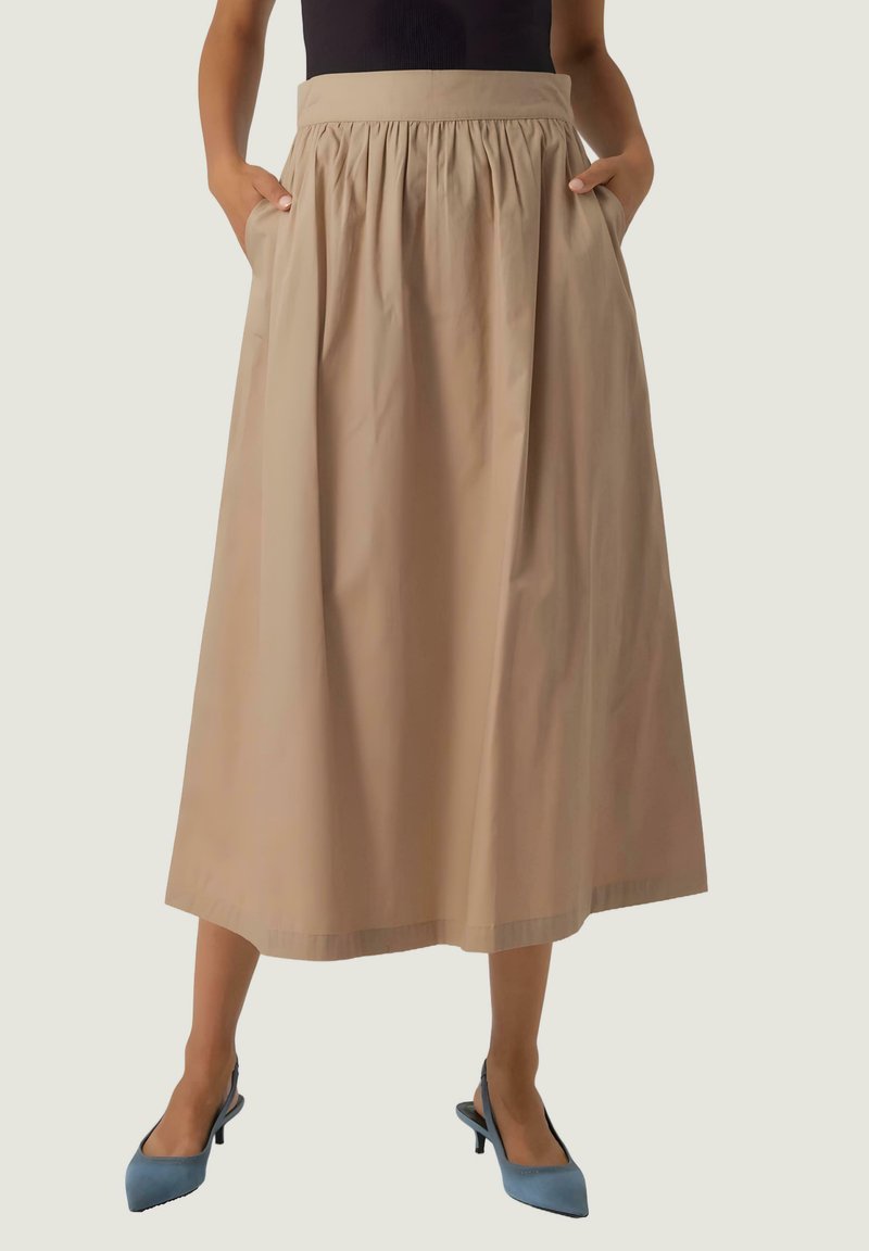 Beige, mid-length kjol med elastisk midja, sidofickor och en slät yta. Bärs med ljusblå, spetsiga skor.