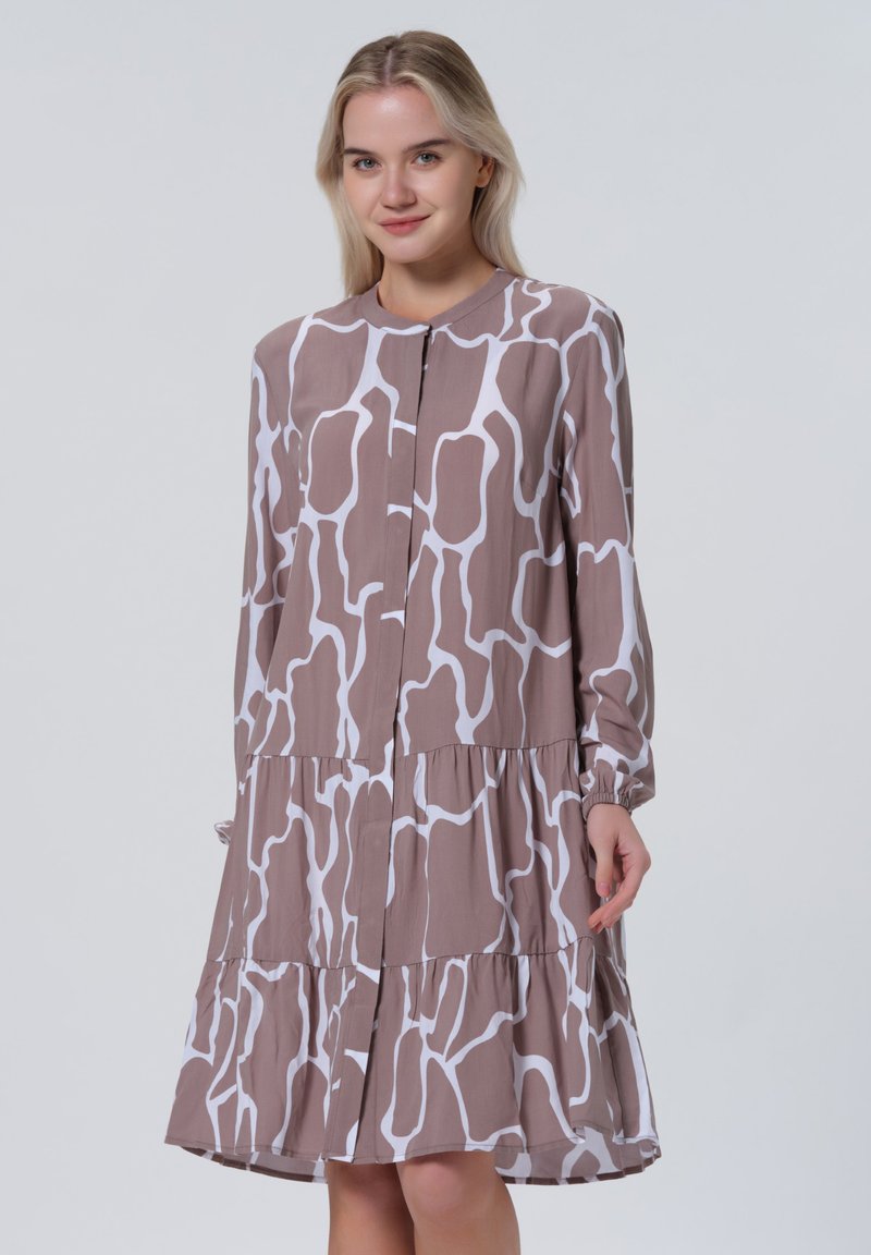 Braun-weiß gemustertes Kleid mit langen Ärmeln, Knopfverschluss, gestuftem Design und weichem Stoff. Lässiger und entspannter Schnitt.