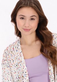 Cardigan tricotat multicolor cu o croială lejeră; prezintă un model presărat pe un fundal alb; asortat cu un top de trening lavandă.