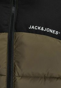 Doudoune comportant une partie supérieure noire et une partie inférieure vert olive, avec une fermeture éclair centrale et un logo blanc "JACK & JONES".