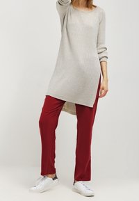 Light gray ribbed tunic with long sleeves and side slits, paired with burgundy pants. Look features white sneakers with gray accents.