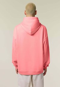 Hoodie rosa con un grande cappuccio e maniche lunghe e larghe. Tessuto liscio e morbido con polsini e orlo a coste. Design minimalista, senza motivi visibili.