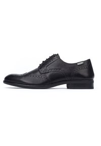 Scarpe da uomo in pelle nera con dettagli brogue, punta arrotondata e tacco basso e elegante. I lacci si estendono dall'apertura della scarpa.