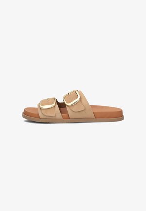 Tan suede slide sandal featuring two wide straps with gold-tone buckles, a flat brown sole, and a smooth texture throughout.