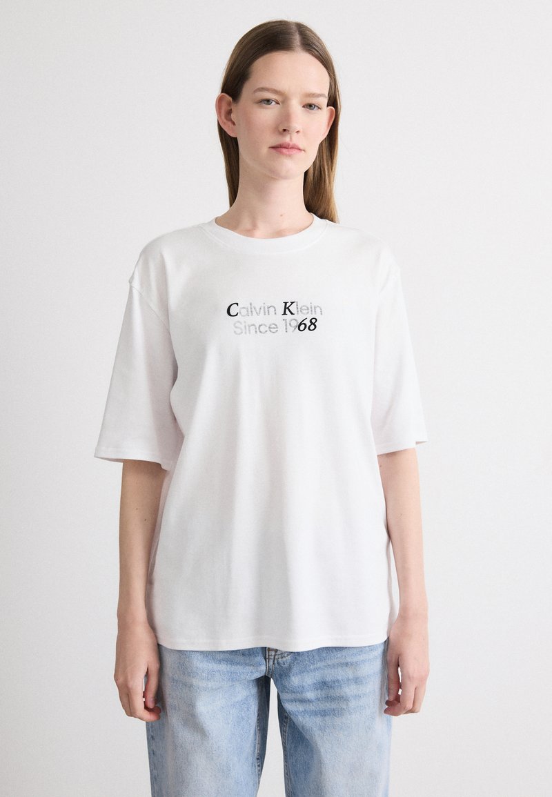 Witte T-shirt met korte mouwen, voorzien van een zwarte opdruk "Calvin Klein Since 1968". Gemaakt van zachte katoen, heeft het een relaxte pasvorm en een ronde hals.