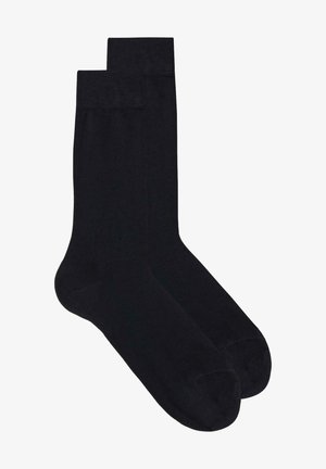 Calzini neri realizzati in un tessuto liscio e elasticizzato con un design classico. Presentano una punta e un tallone rinforzati, con polsini a coste nella parte superiore.