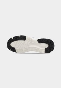 Η μαύρη και άσπρη σόλα του αθλητικού παπουτσιού διαθέτει υφασμένο λάστιχο με πολυκατευθυντικά προφίλ πέδησης, προσφέροντας κράτημα και ανθεκτικότητα.