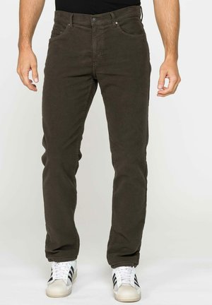 Pantalons coton vert foncé avec cinq poches, une coupe slim et un tissu légèrement texturé. Associés à des baskets blanches avec des rayures noires.