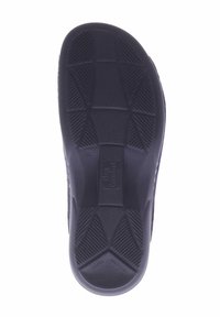 Black rubber shoe sole featuring a tread pattern with raised lines and grooves for grip, labeled with size and brand details.