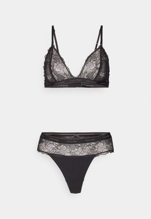 Bralette in pizzo nero con spalline regolabili e motivo floreale. Thong coordinato con rifiniture in pizzo e vita con logo. Entrambi realizzati in tessuto morbido.