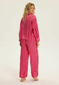 Czerwono-różowe, pasek jedwabne piżamy o luźnym kroju, z zapięciem na guziki przy mankietach i szerokich nogawkach, charakteryzujące się gładką, błyszcząca teksturą.