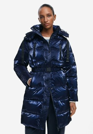 Tumesinine puffertagi, läikivast kangast. Omab kitsendatud talje, kapuutsi ja musti aktsente koos tõmblukkudega taskutega. Quilted disain kogu toote ulatuses.