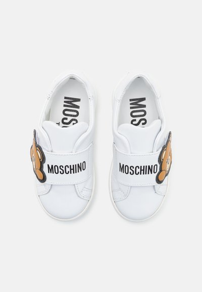 Hvite sneakers med borrelåsspenner, med et bjørnedesign og "MOSCHINO"-merke. Glatt lærmateriale og rund form.