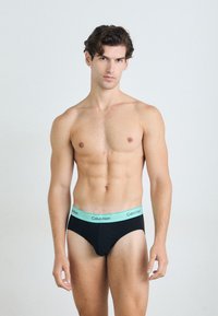 Boxeri din bumbac negri cu un tiv albastru deschis, ce prezintă logo-ul Calvin Klein. Cusăturile plate și ajustarea strânsă îmbunătățesc confortul și suportul.