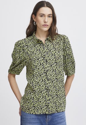 Schwarzgemusterte Hemdbluse mit Blumenmuster, die grüne und weiße Blumen zeigt. Kurze Puffärmel und weicher Stoff. 