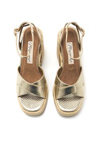 Sandalias cuñas metálicas doradas con un diseño de tiras cruzadas texturizadas, correa de tobillo ajustable y una suela de tejido en color natural.
