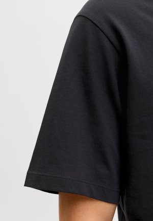 Črna kratka majica s kratkimi rokavi iz mehkega bombaža, z okrolim izrezom in urejenimi šivi ob rokavih in robu.