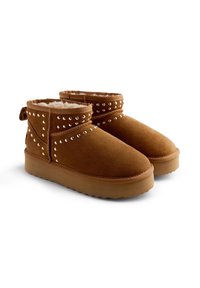 Botas de tobillo de ante marrón con un suave forro de piel sintética, decoradas con tachuelas plateadas a lo largo de la parte superior y una suela de goma para mayor tracción.